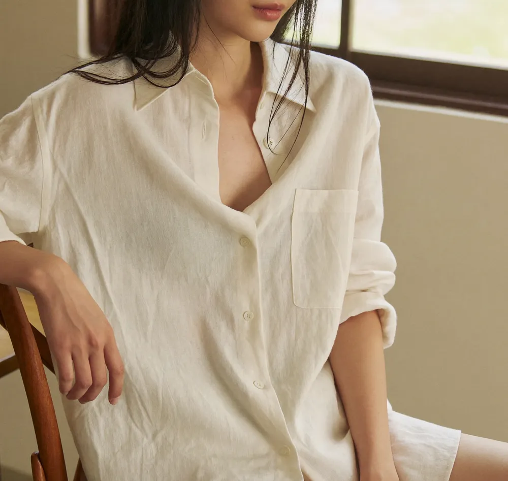 창가에 앉아 아이보리 리넨 셔츠를 입은 모델의 상반신 룩북 컷